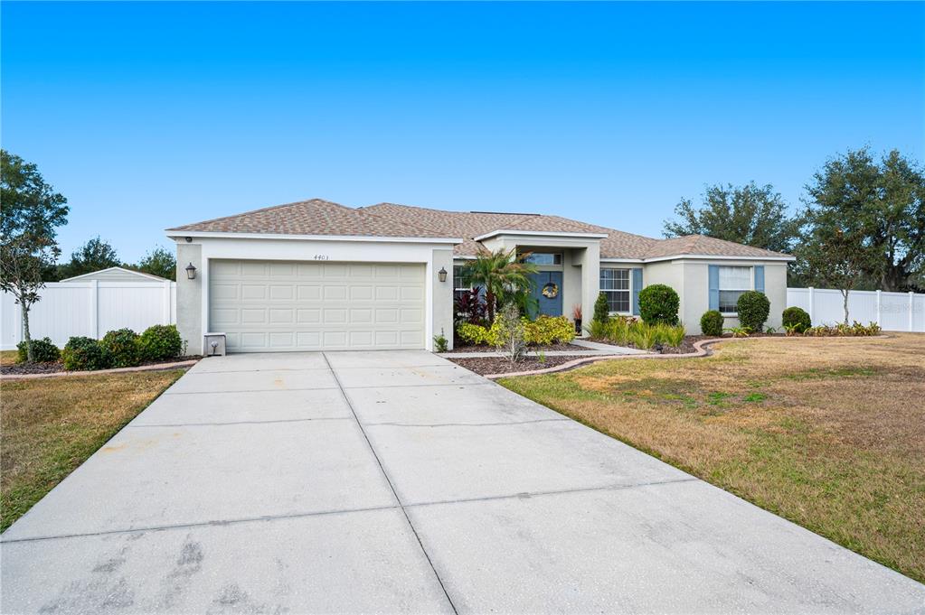 A single-story house with a two-car garage, light-colored stucco exterior, and a concrete driveway — 4403 AVONDALE GROVES STREET, PLANT CITY, FL