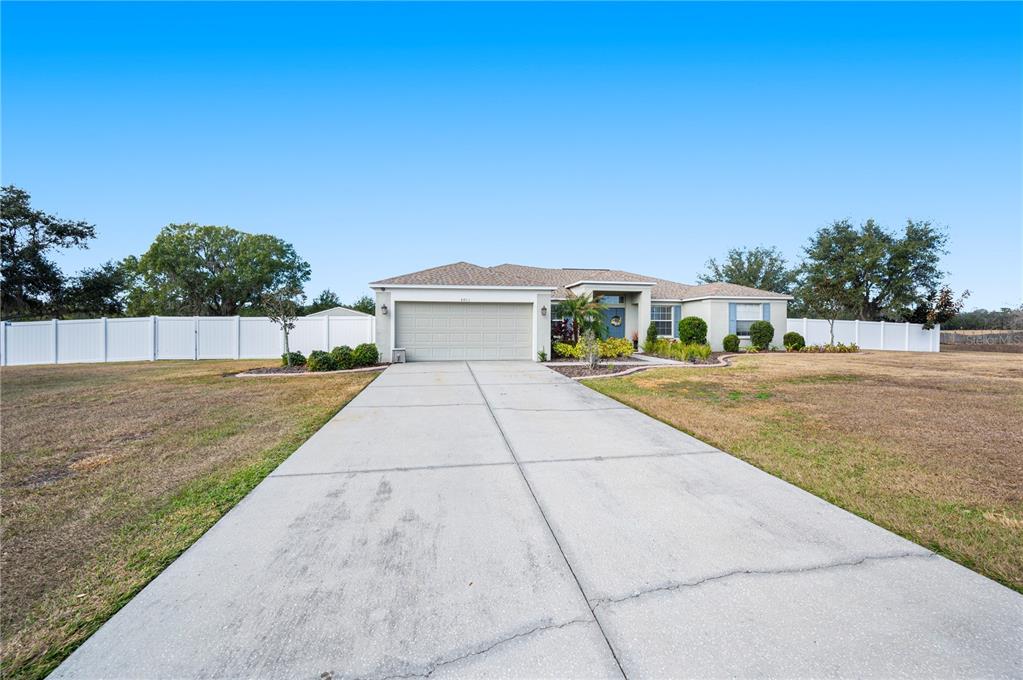 A single-story house with a beige exterior, a two-car garage, and a concrete driveway — 4403 AVONDALE GROVES STREET, PLANT CITY, FL