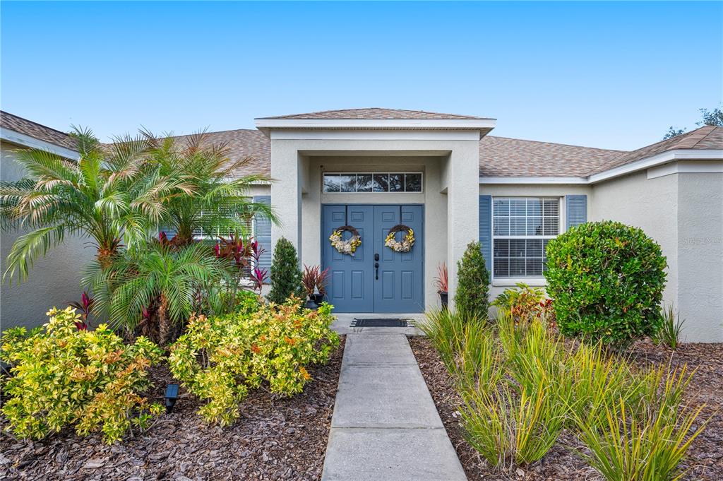 The front exterior of a single-story house features a blue double door and landscaping — 4403 AVONDALE GROVES STREET, PLANT CITY, FL