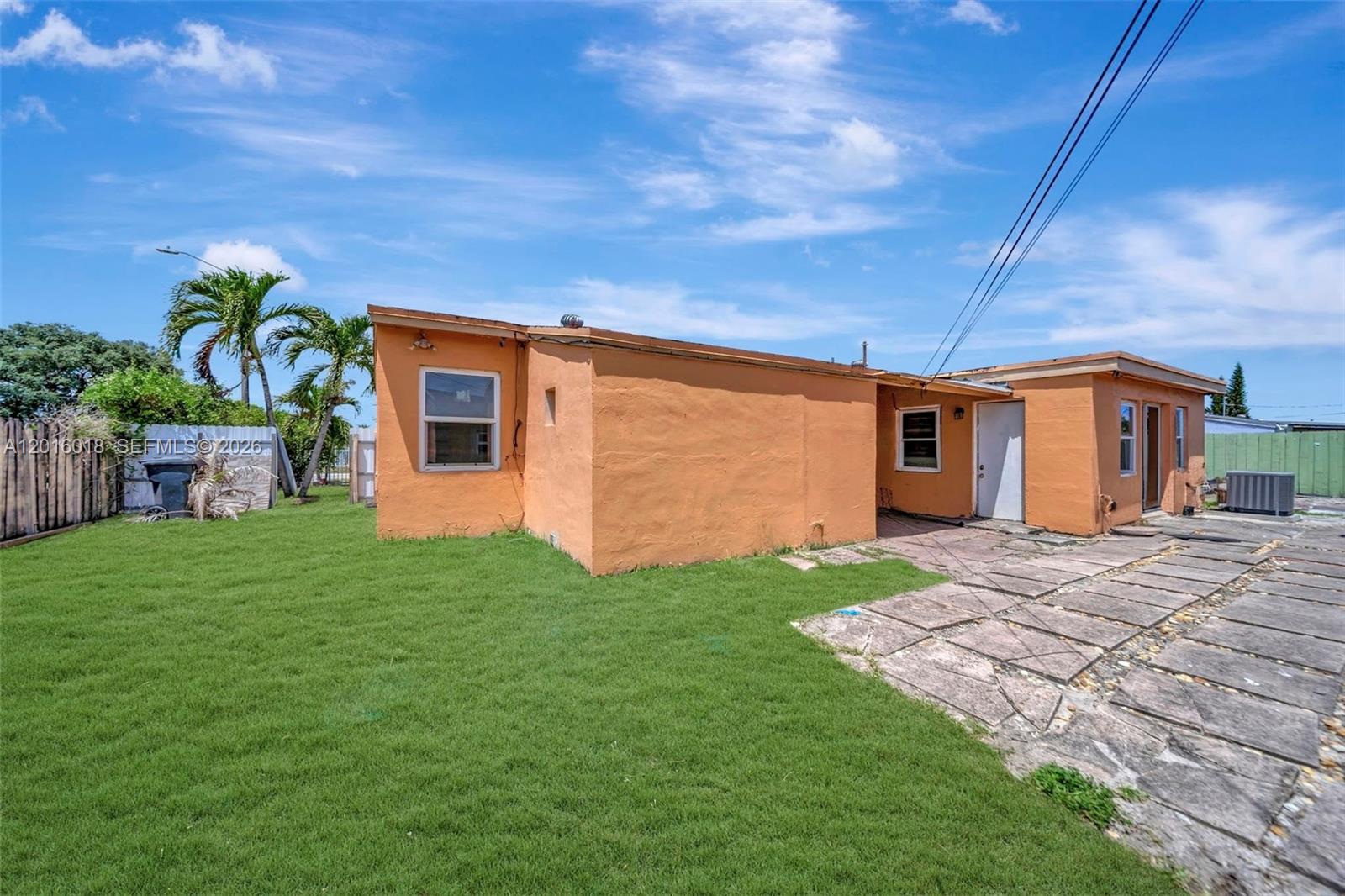 The exterior of a peach-colored house features a grassy yard and a stone patio — 2890 NW 160th St, Miami Gardens FL 33054, MIAMI GARDENS, FL