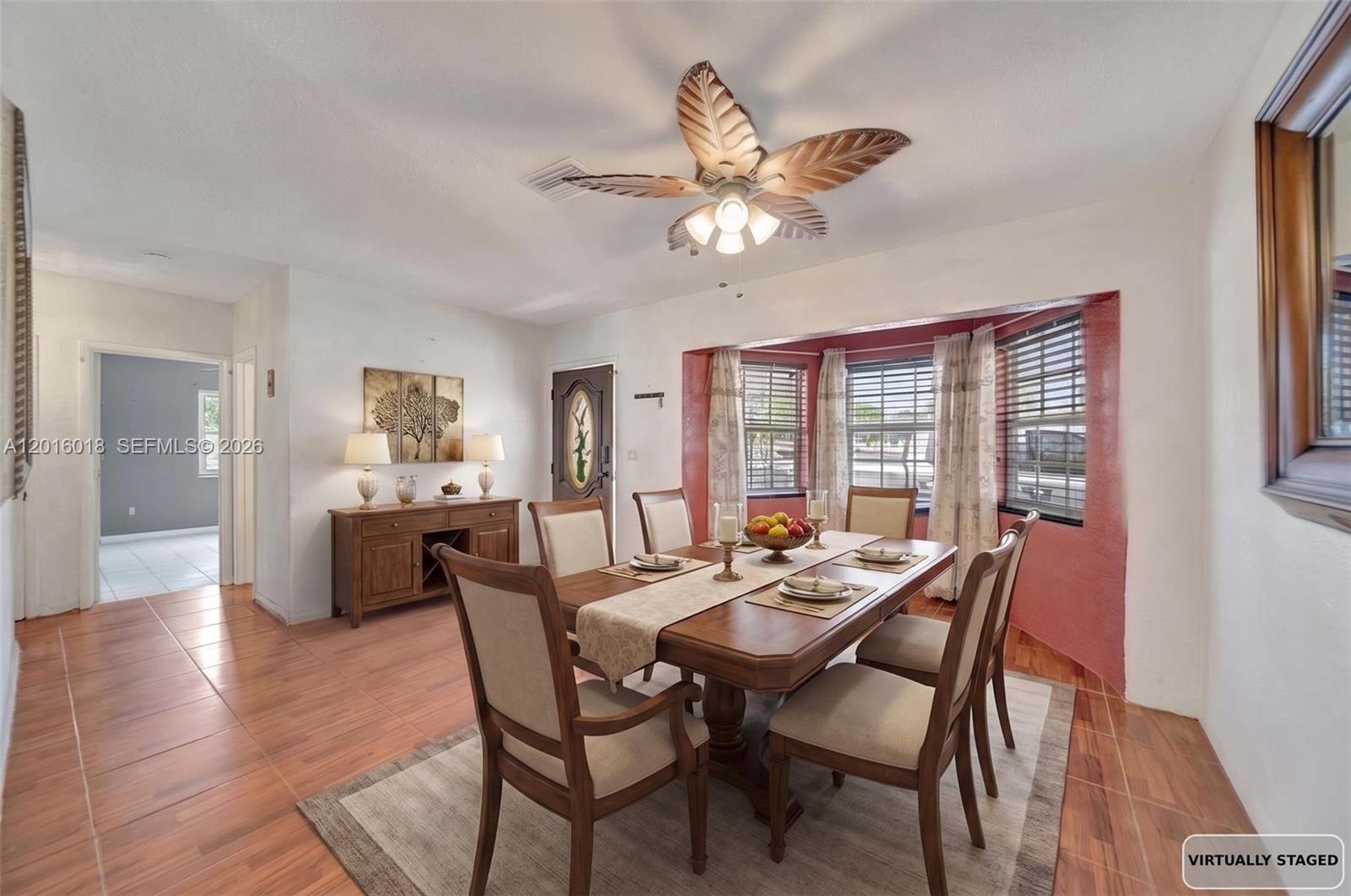 A dining room features a wooden table, chairs, a ceiling fan, and a red-accented window — 2890 NW 160th St, Miami Gardens FL 33054, MIAMI GARDENS, FL