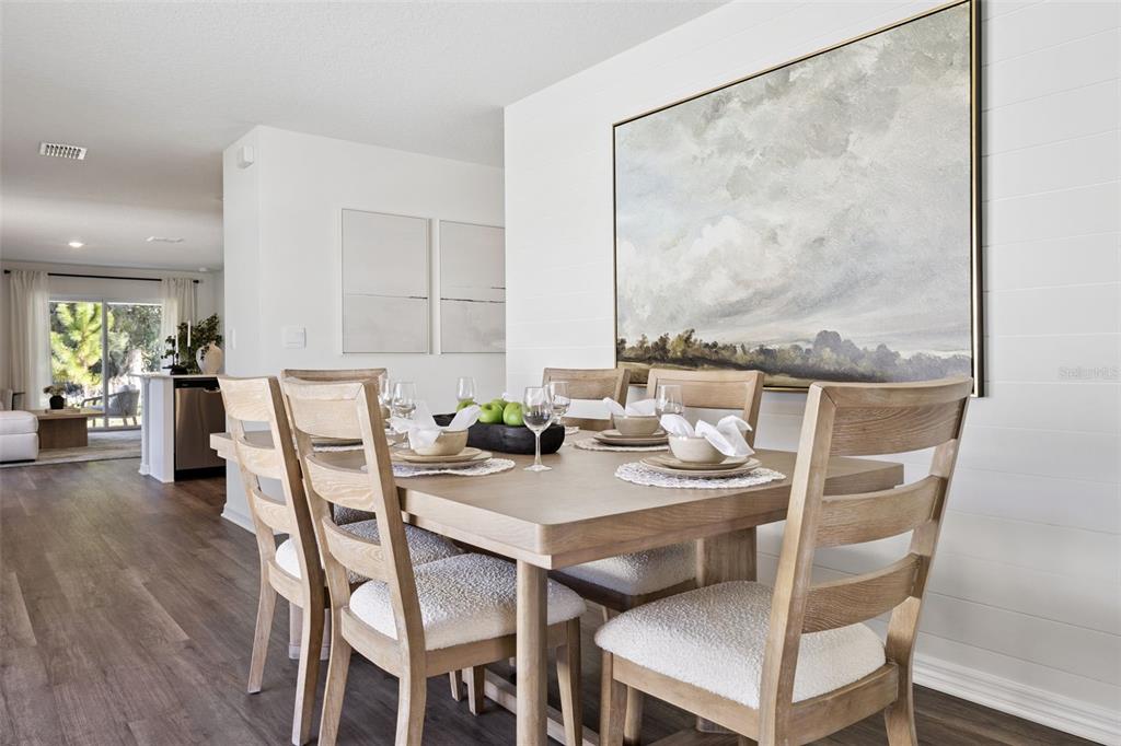 A dining room features a wooden table with six chairs and a large landscape painting — 7947 FORREST FOX WAY, LAKELAND, FL
