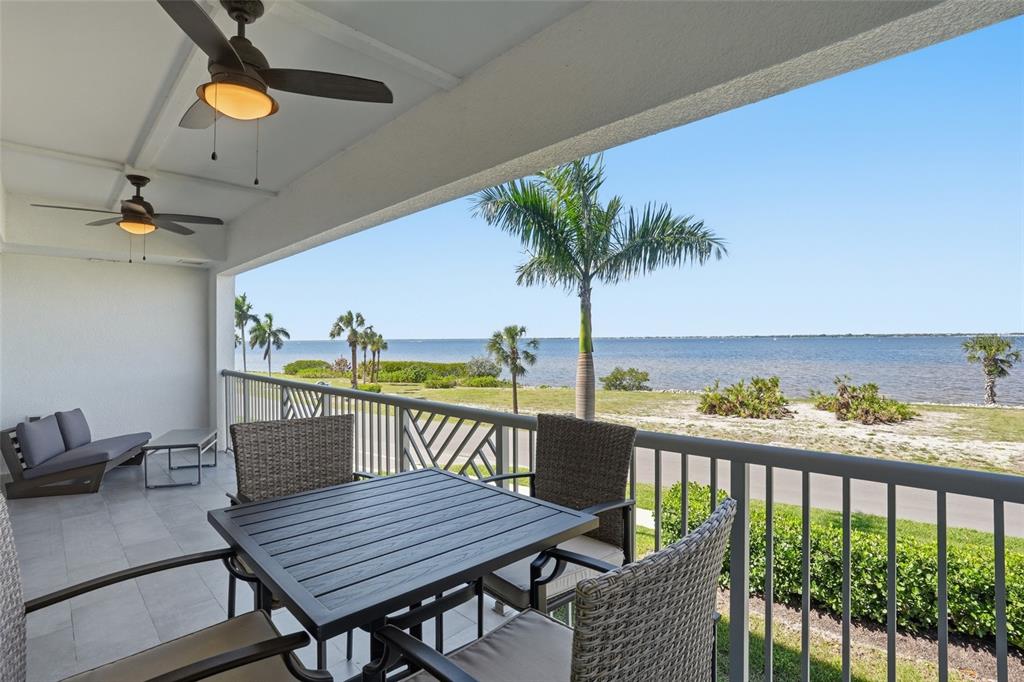 A covered balcony with outdoor furniture overlooks a grassy lawn and a large body of water — 1425 PARK BEACH CIRCLE UNIT 124, PUNTA GORDA, FL