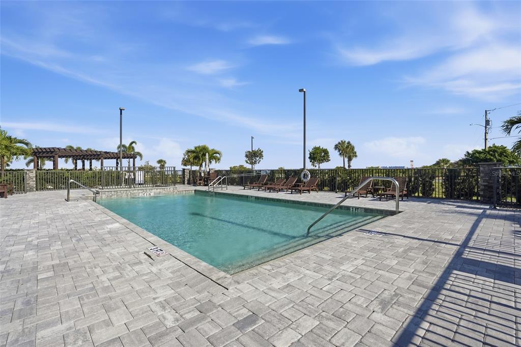 An outdoor swimming pool with a paved deck, lounge chairs, and a pergola — 1425 PARK BEACH CIRCLE UNIT 124, PUNTA GORDA, FL