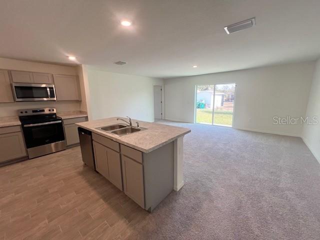 A kitchen with gray cabinets and an island opens into a carpeted living area — 2116 HANSON STREET, PORT CHARLOTTE, FL