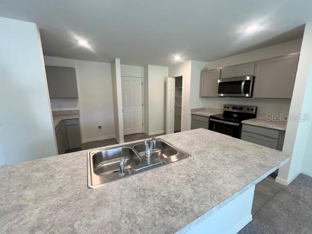 A kitchen features gray cabinets, a central island with a sink, and stainless steel appliances — 2116 HANSON STREET, PORT CHARLOTTE, FL