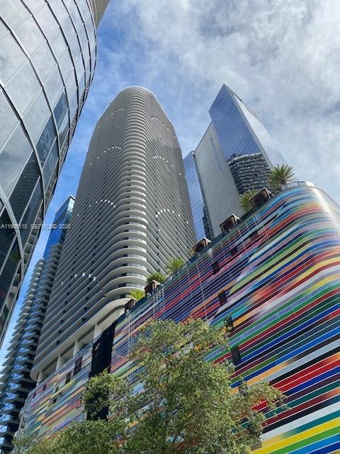 A low-angle view of several modern skyscrapers, including one with a colorful, striped facade — 801 S Miami Ave # 604, Miami FL 33130, MIAMI, FL