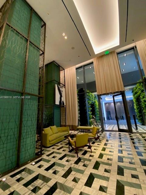 A modern lobby features a green geometric wall, yellow armchairs, and a patterned marble floor — 801 S Miami Ave # 604, Miami FL 33130, MIAMI, FL