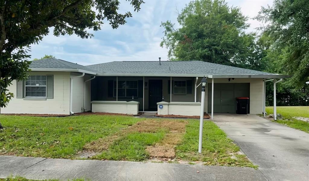 A single-story house with a beige exterior, a screened-in porch, and an attached garage — 3560 SW 150TH LANE ROAD, OCALA, FL