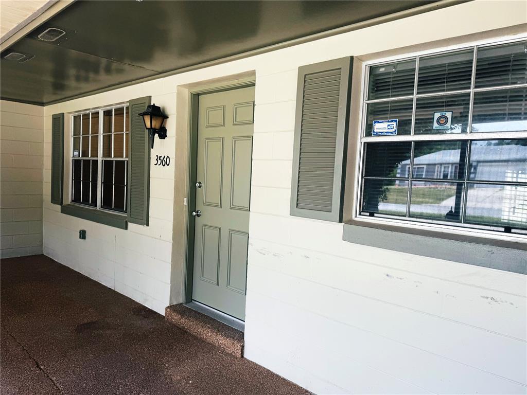A covered porch leads to a green front door with a house number and windows — 3560 SW 150TH LANE ROAD, OCALA, FL