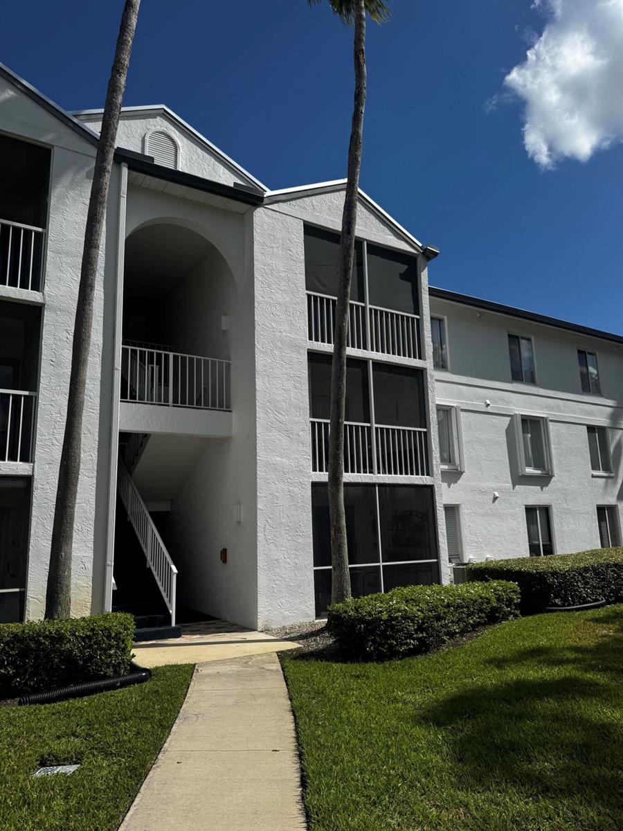 A white multi-story apartment building with screened balconies and palm trees on a sunny day — 2502 SE Anchorage Cove # 3, FL 34952, FL