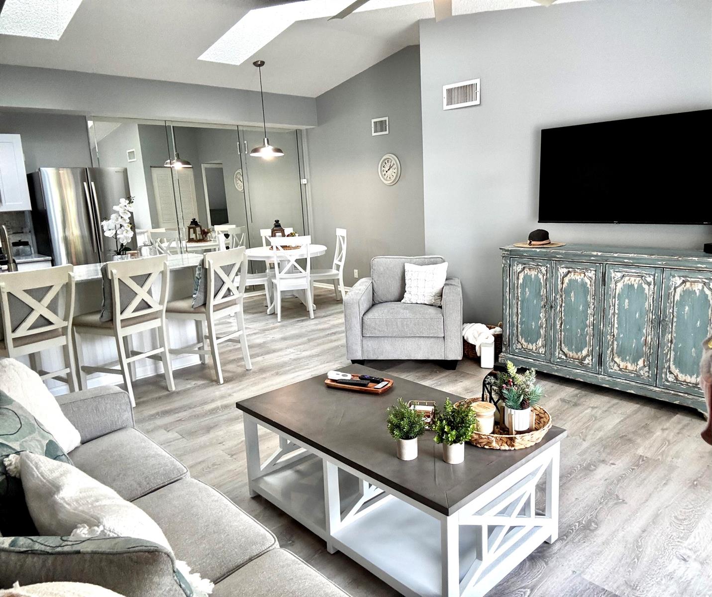 A living room and dining area featuring gray walls, wood-look flooring, and a distressed blue cabinet — 2502 SE Anchorage Cove # 3, FL 34952, FL