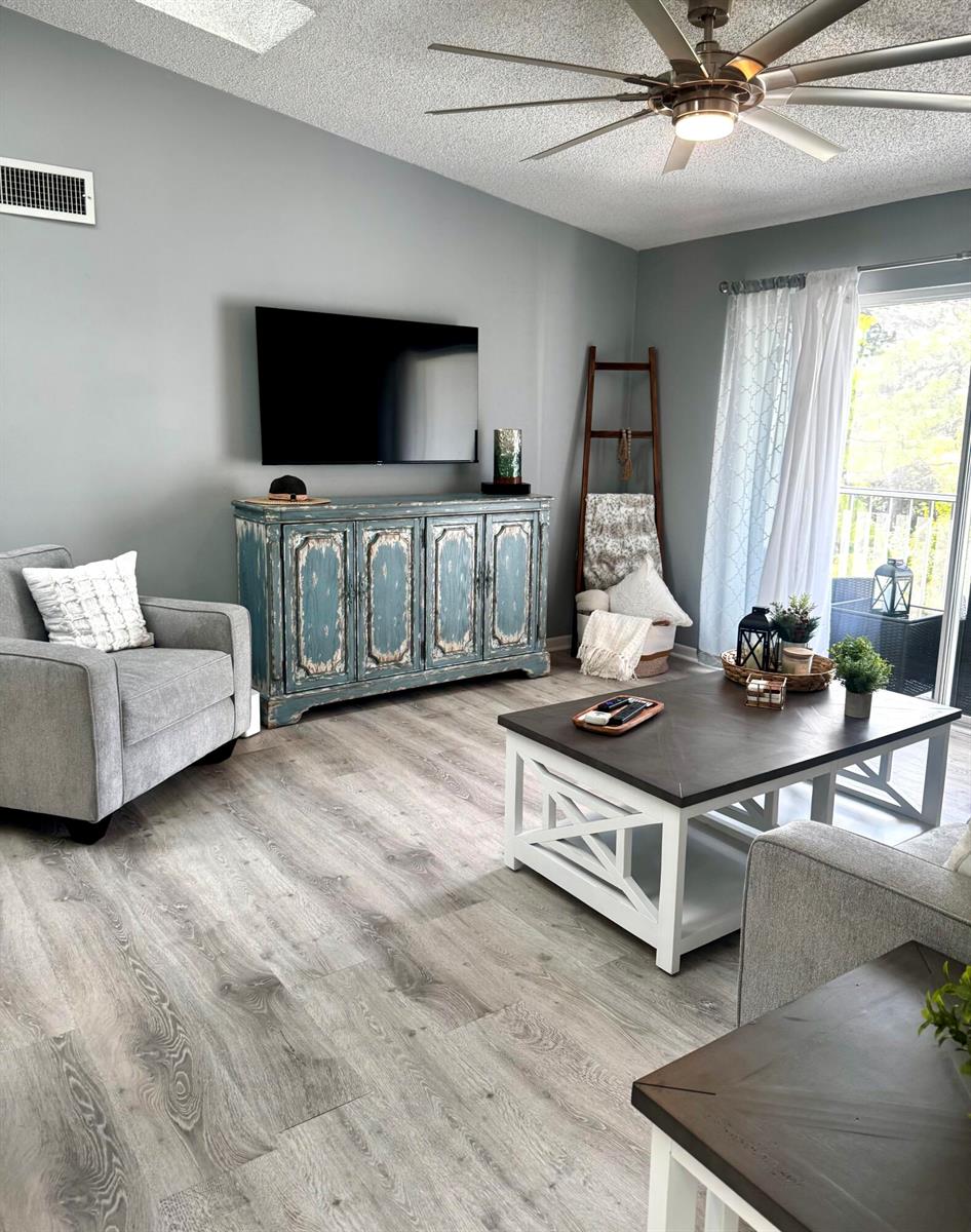 A living room features gray walls, wood-look flooring, a blue distressed sideboard, and a coffee table — 2502 SE Anchorage Cove # 3, FL 34952, FL