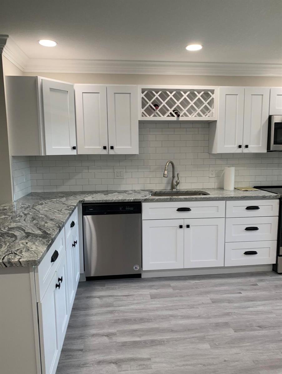 A kitchen features white cabinets, granite countertops, a subway tile backsplash, and stainless steel appliances — 9199 Pecky Cypress Lane # 7d, Boca Raton FL 33428, BOCA RATON, FL