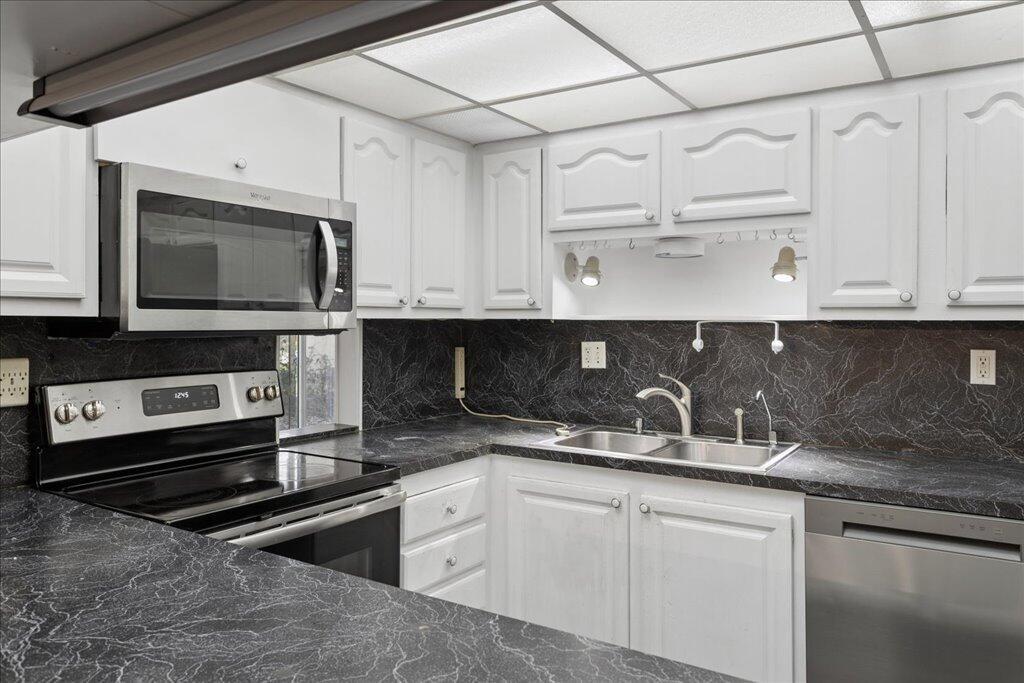 A kitchen features white cabinets, dark marble-patterned countertops, and stainless steel appliances — 9491 Evergreen Place # 108, Davie FL 33324, DAVIE, FL