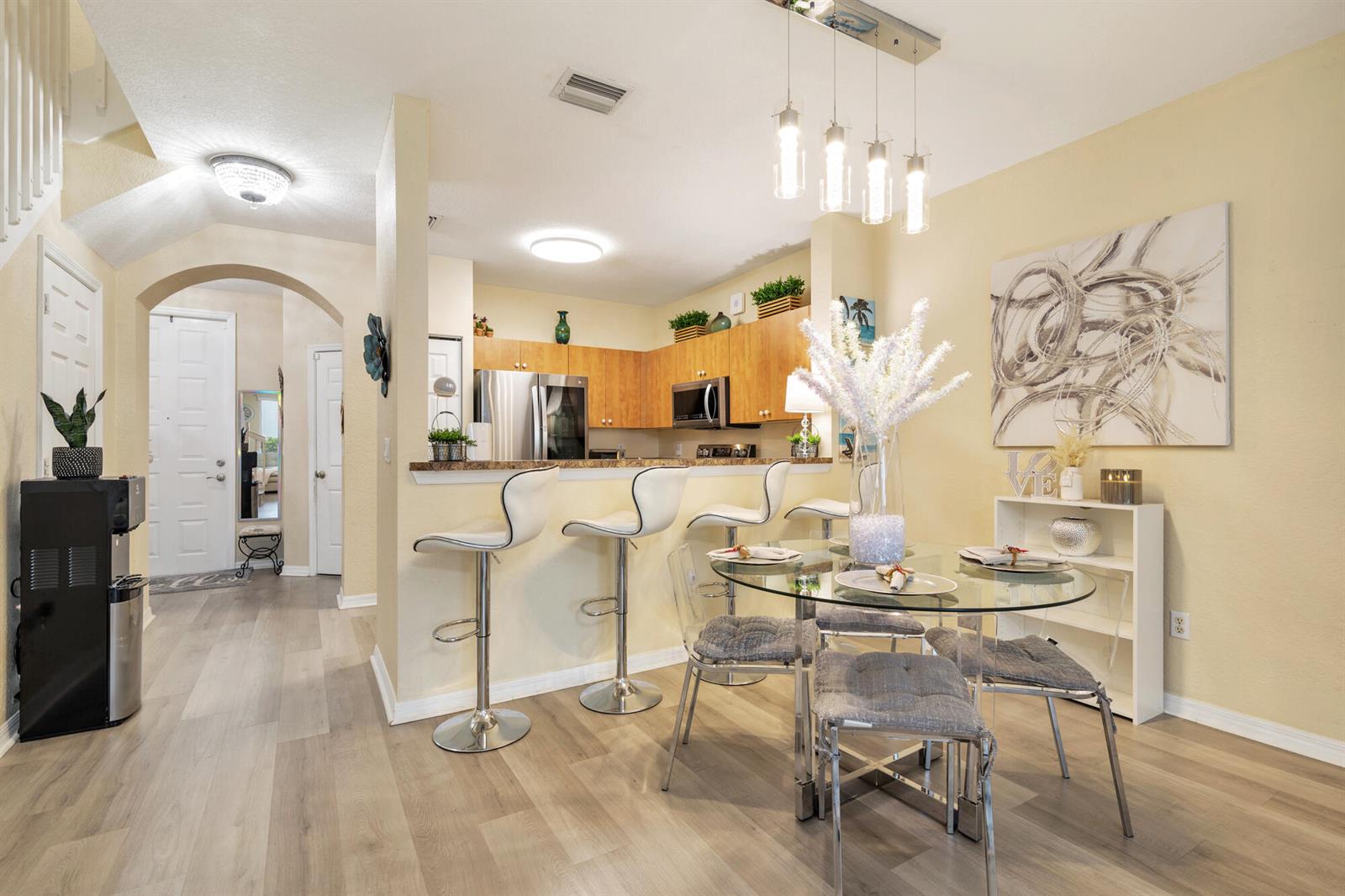 A kitchen with wooden cabinets and a breakfast bar next to a glass dining table — 3725 Oleander Terrace, Riviera Beach FL 33404, RIVIERA BEACH, FL