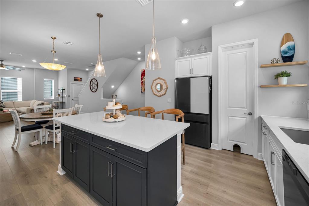 A kitchen features a dark blue island with a white countertop and light wood flooring — 2458 MANGUM COURT, SARASOTA, FL