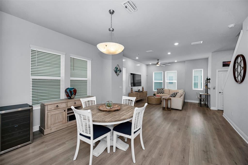 A dining area with a round wooden table flows into a living room with light flooring — 2458 MANGUM COURT, SARASOTA, FL