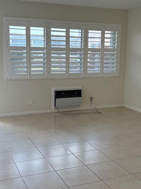 A room with light-colored tile flooring, white plantation shutters, and a wall-mounted air conditioner — 313 Andover # M, West Palm Beach FL 33417, WEST PALM BEACH, FL