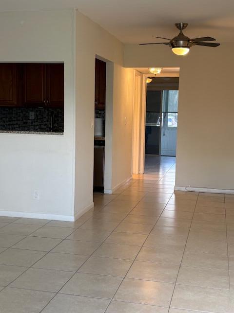 A tiled living area leads to a kitchen pass-through and a hallway with a ceiling fan — 313 Andover # M, West Palm Beach FL 33417, WEST PALM BEACH, FL