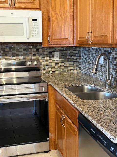 A kitchen features oak cabinets, granite countertops, a stainless steel stove, and a mosaic tile backsplash — 313 Andover # M, West Palm Beach FL 33417, WEST PALM BEACH, FL