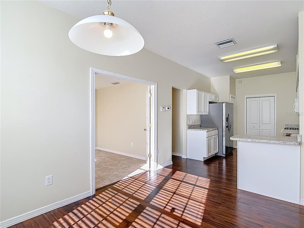 A dining area with wood floors and a pendant light opens into a kitchen — 1931 SASSAFRAS DRIVE, WESLEY CHAPEL, FL