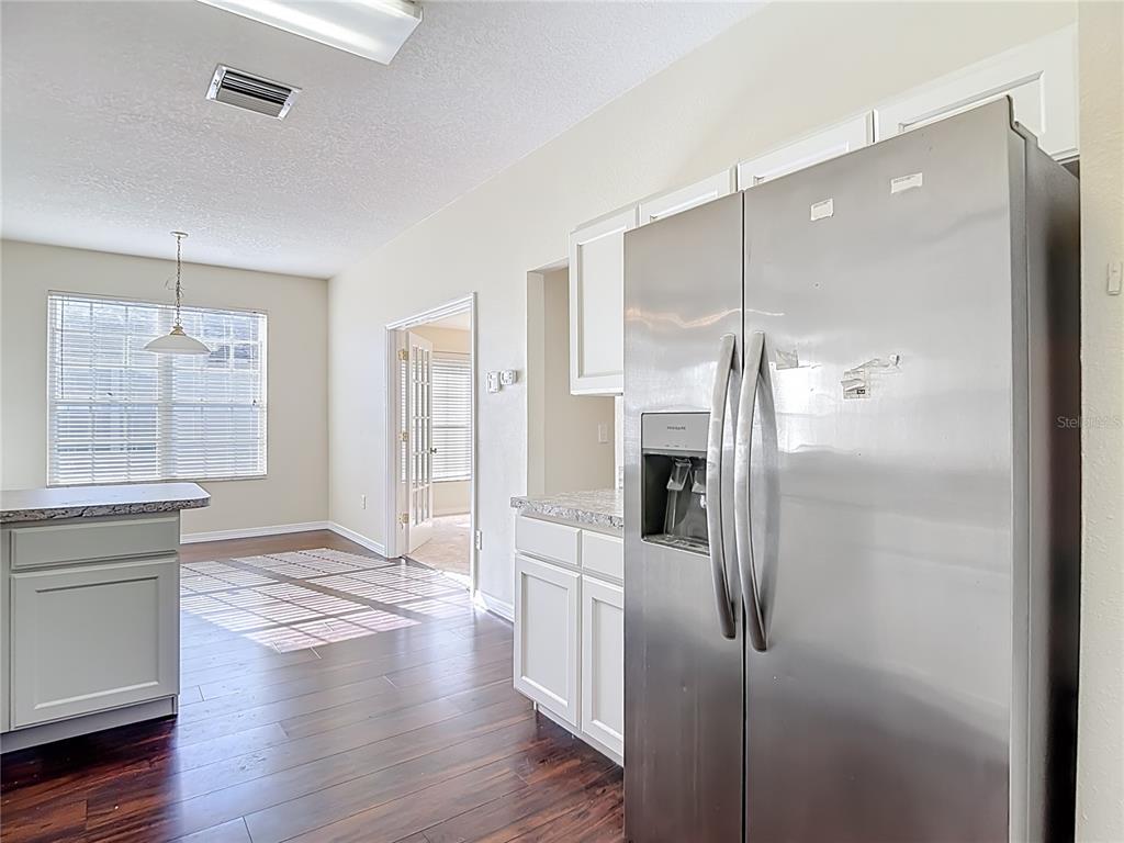 A kitchen with white cabinets, stainless steel appliances, and dark wood flooring — 1931 SASSAFRAS DRIVE, WESLEY CHAPEL, FL