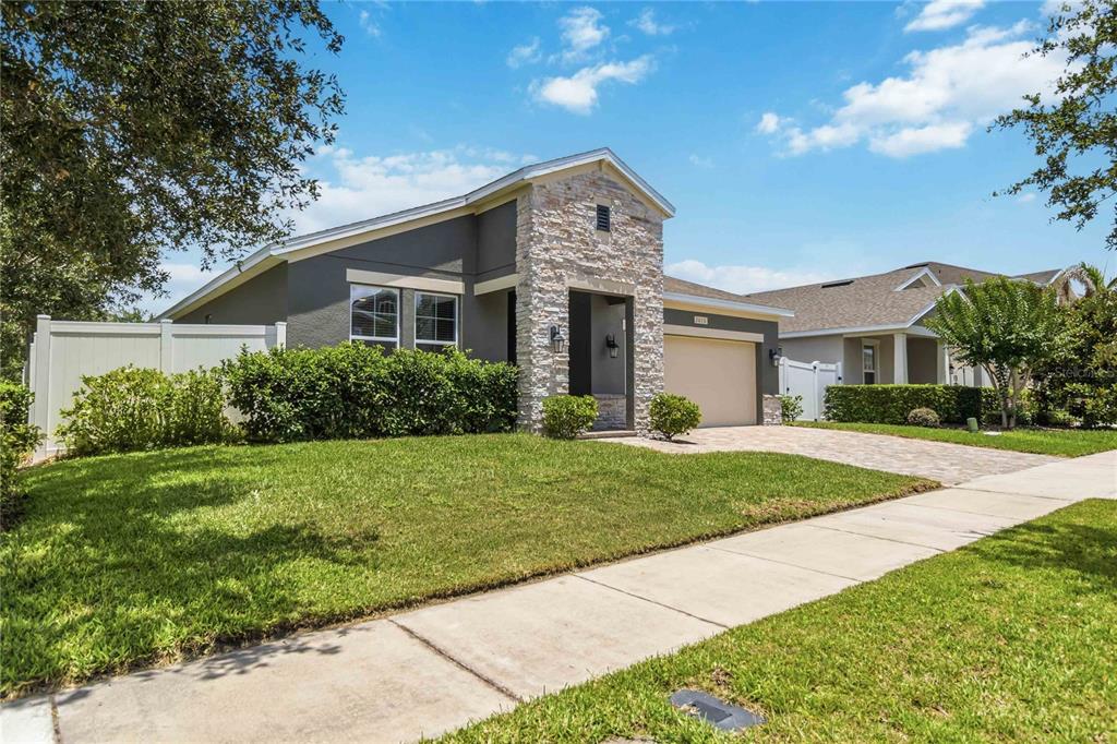 A single-story house with a stone facade, gray stucco, and a paved driveway — 2015 BEACON LANDING CIRCLE, ORLANDO, FL