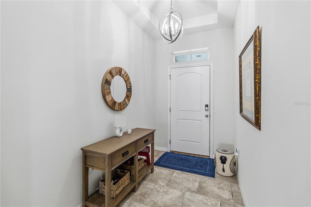 An entryway features a wooden console table, a round mirror, and a white front door — 2015 BEACON LANDING CIRCLE, ORLANDO, FL