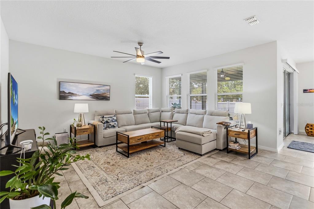 A living room features a large sectional sofa, a wooden coffee table, and tile flooring — 2015 BEACON LANDING CIRCLE, ORLANDO, FL