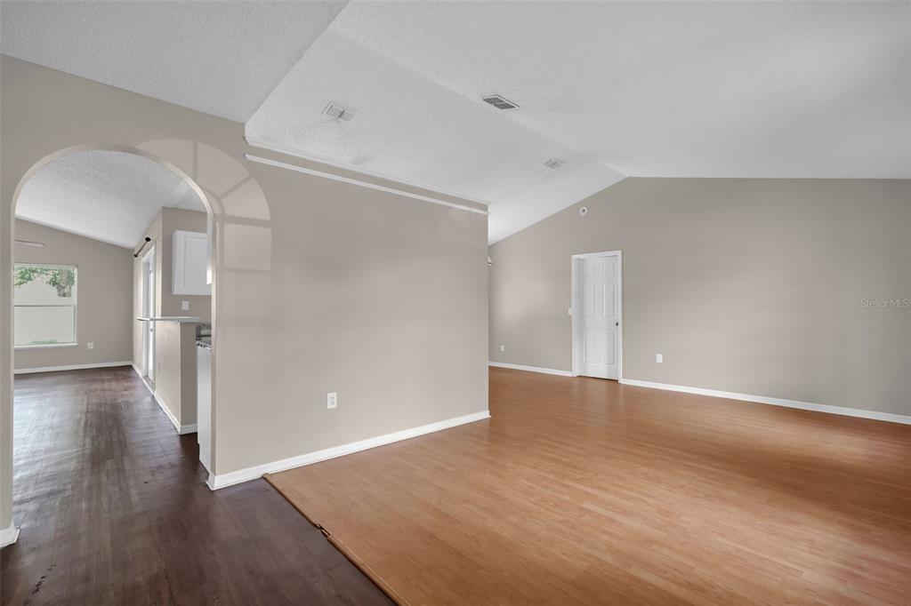 An open-concept living area features light-colored walls, wood-look flooring, and an arched entryway — 525 CARLSBAD DRIVE, KISSIMMEE, FL