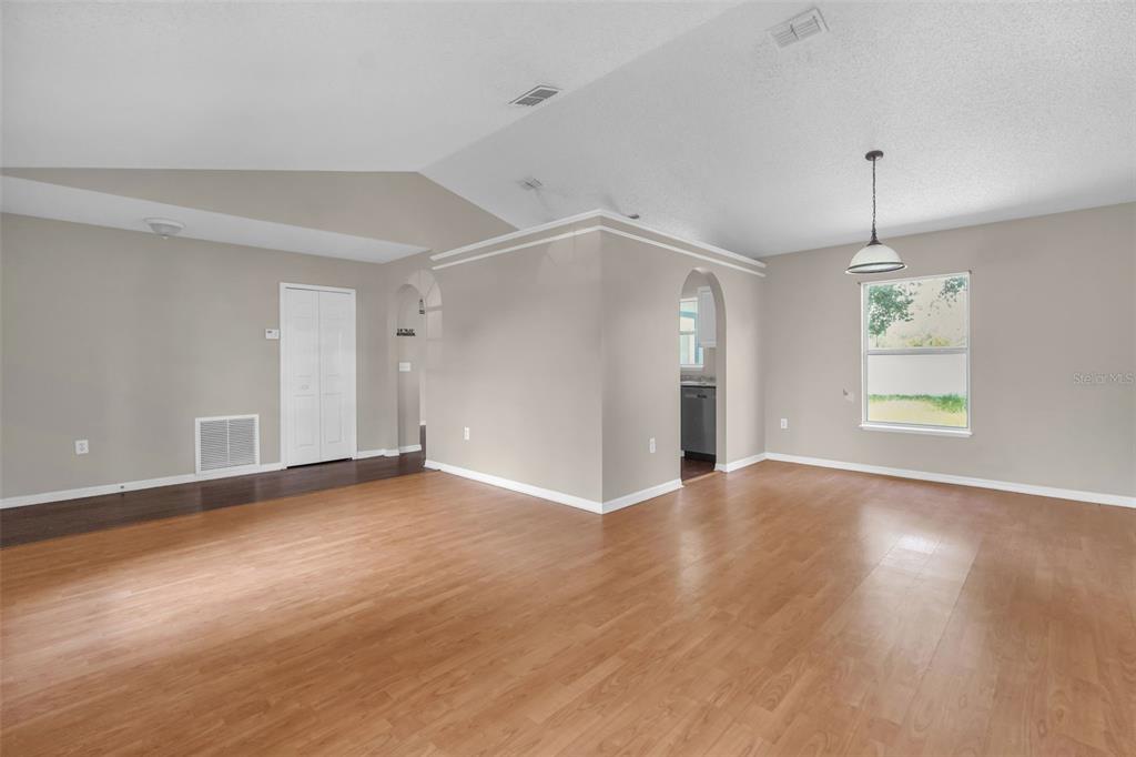 An open-concept living area features light-colored walls, wood-look flooring, arched windows, and an arched entryway — 525 CARLSBAD DRIVE, KISSIMMEE, FL