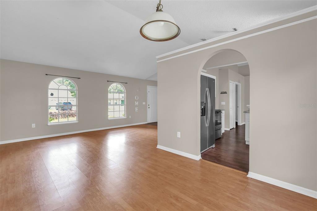 A kitchen features white cabinets, granite-look countertops, stainless steel appliances, and dark wood-look flooring — 525 CARLSBAD DRIVE, KISSIMMEE, FL