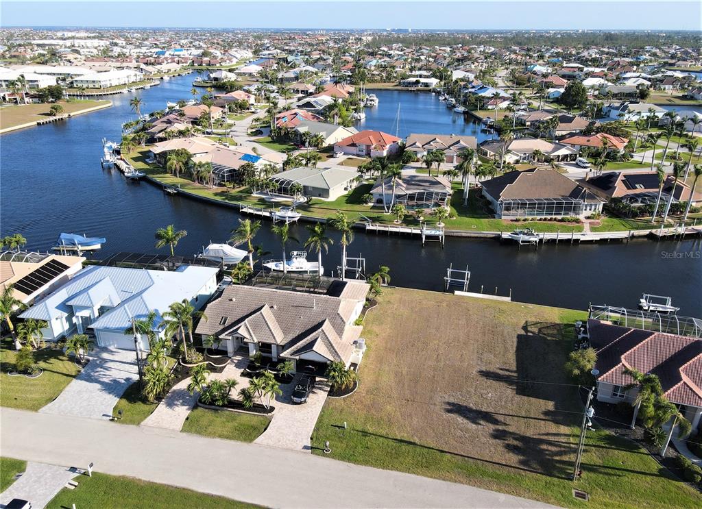 An aerial view shows a waterfront residential lot next to a house with a boat dock — 1418 SEA GULL COURT, PUNTA GORDA, FL
