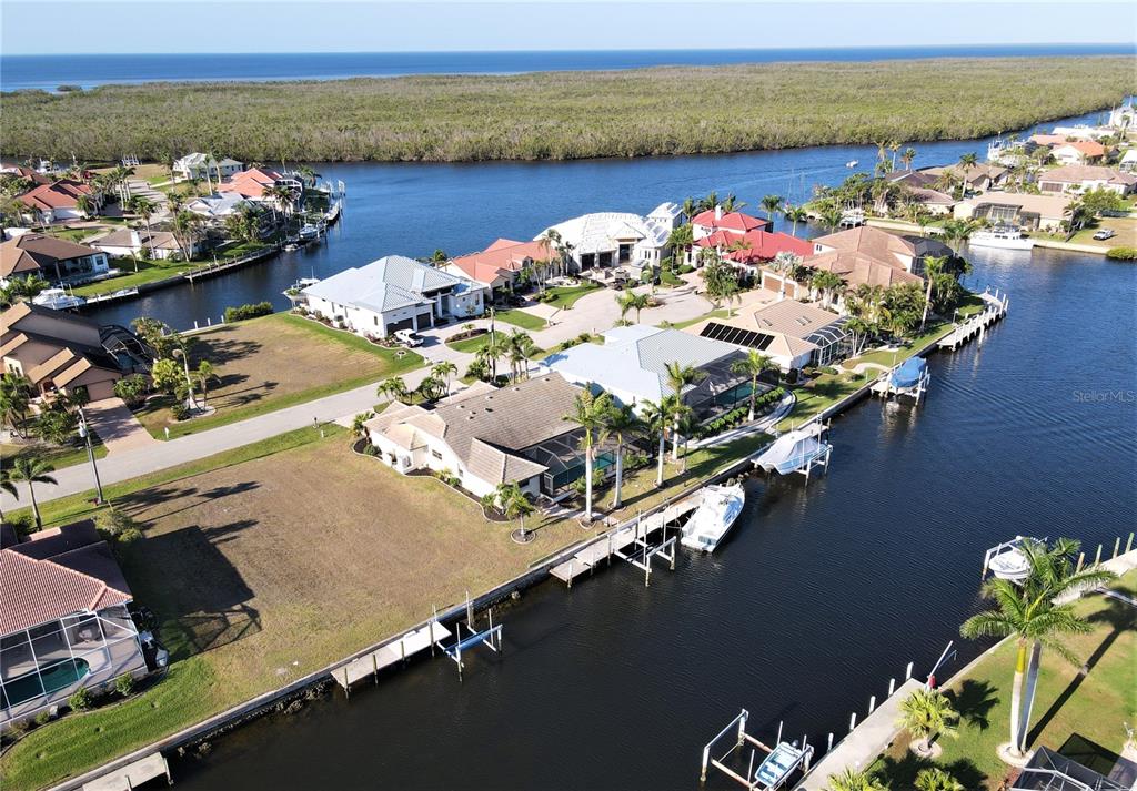 An aerial view shows waterfront houses with private docks along a canal near mangroves — 1418 SEA GULL COURT, PUNTA GORDA, FL