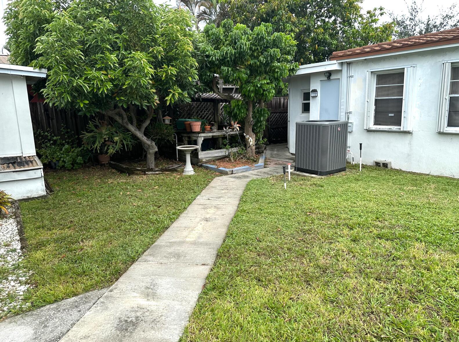 A concrete walkway leads through a grassy backyard toward a house with an AC unit — 31 SW 10th Street # 3, Dania Beach FL 33004, DANIA BEACH, FL