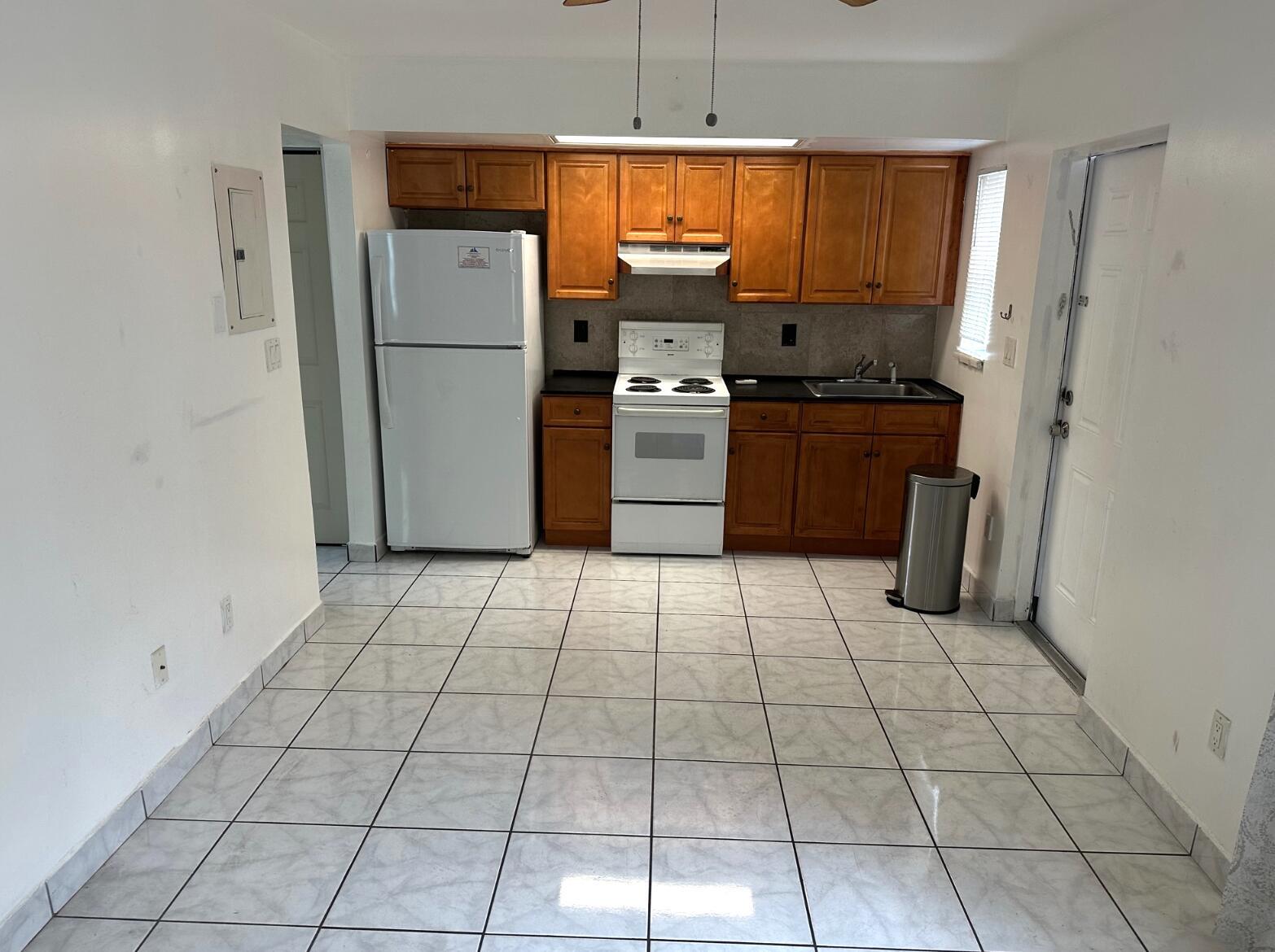 A kitchen with white appliances, wooden cabinets, dark countertops, and light-colored tiled flooring — 31 SW 10th Street # 3, Dania Beach FL 33004, DANIA BEACH, FL