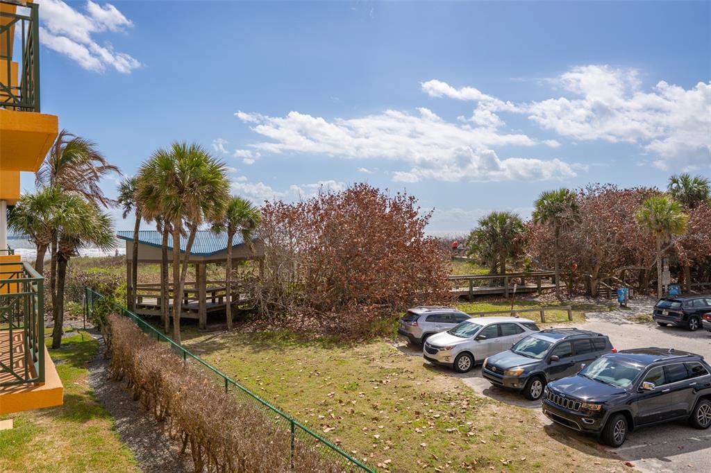 An elevated view of a parking lot, palm trees, a wooden gazebo, and the ocean — 8472 RIDGEWOOD AVENUE UNIT 201, CAPE CANAVERAL, FL