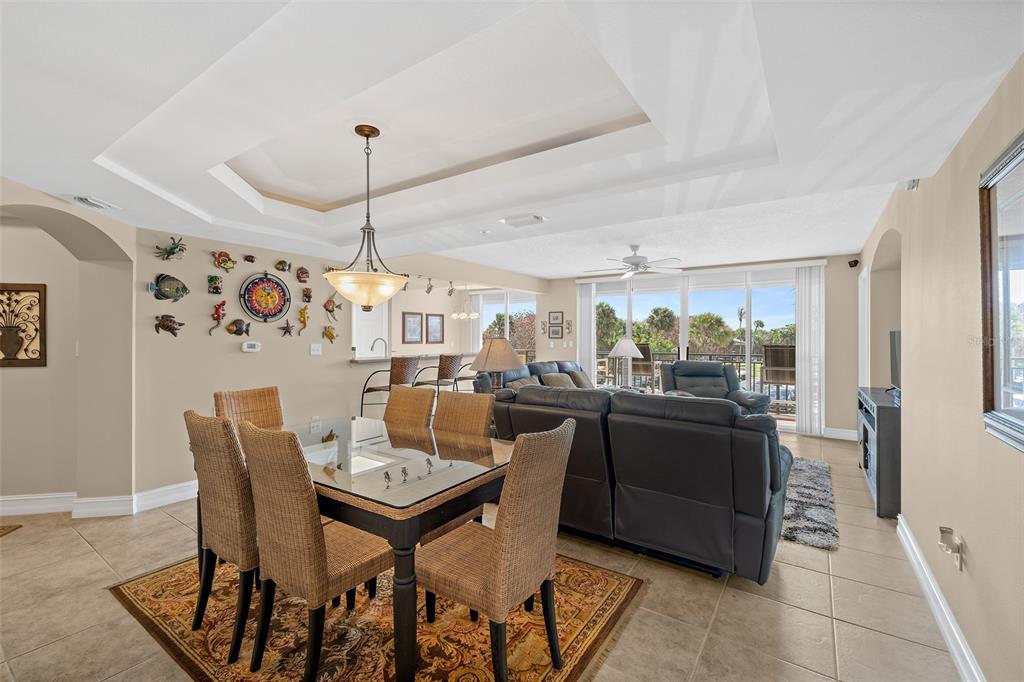 A dining area with a glass table and wicker chairs opens into a living room — 8472 RIDGEWOOD AVENUE UNIT 201, CAPE CANAVERAL, FL