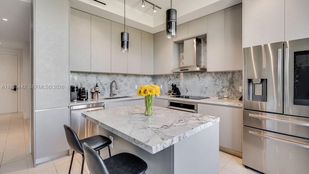 A modern kitchen features gray cabinetry, marble countertops, a central island, and stainless steel appliances — 1030 15th St # 201, Miami Beach FL 33139, MIAMI BEACH, FL