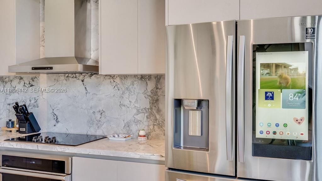 A modern kitchen features white cabinetry, marble countertops, a stainless steel range hood, and a smart refrigerator — 1030 15th St # 201, Miami Beach FL 33139, MIAMI BEACH, FL