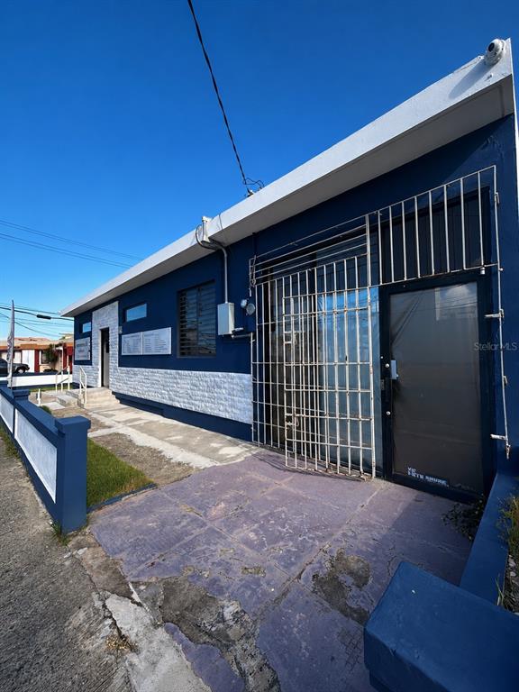 A blue and white commercial building exterior features a metal security gate over the entrance — Avenida Font Martelo FLOR GERENA UNIT 110, HUMACAO, PR