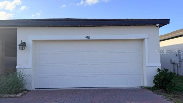 The exterior of a house features a white garage door, a brick driveway, and a lantern — 4913 KAIA AVENUE, WINTER HAVEN, FL