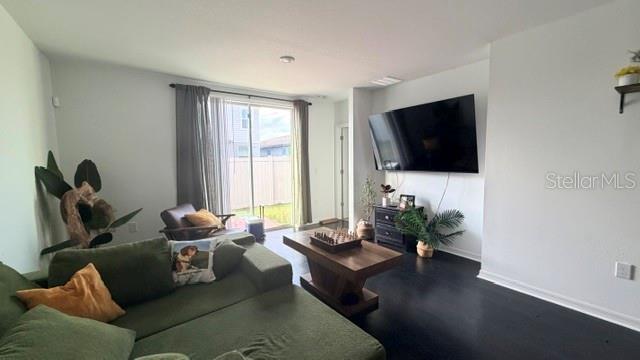 A living room features a green sectional sofa, a coffee table, and a wall-mounted television — 4913 KAIA AVENUE, WINTER HAVEN, FL