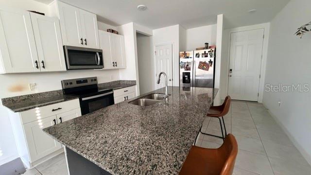 A kitchen features white cabinets, granite countertops, a center island with bar stools, and stainless appliances — 4913 KAIA AVENUE, WINTER HAVEN, FL