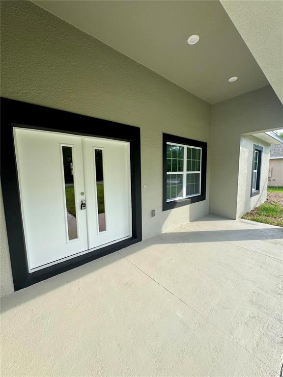A covered concrete porch features a white double door and windows with black trim — 152 W DIEGO PLACE, CITRUS SPRINGS, FL