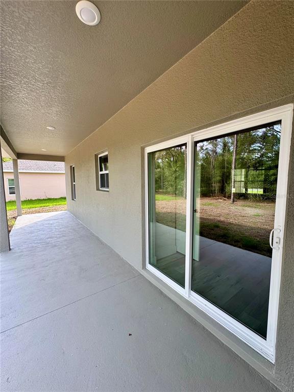 A covered concrete patio features a sliding glass door and recessed ceiling lights — 152 W DIEGO PLACE, CITRUS SPRINGS, FL
