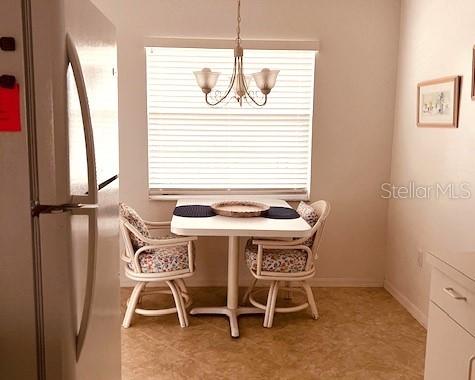A small dining area features a white table, two wicker chairs, and a hanging chandelier — 8735 OLDE HICKORY AVENUE UNIT 8302, SARASOTA, FL