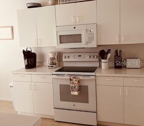 A kitchen features white cabinets, a white electric range, and a built-in microwave — 8735 OLDE HICKORY AVENUE UNIT 8302, SARASOTA, FL