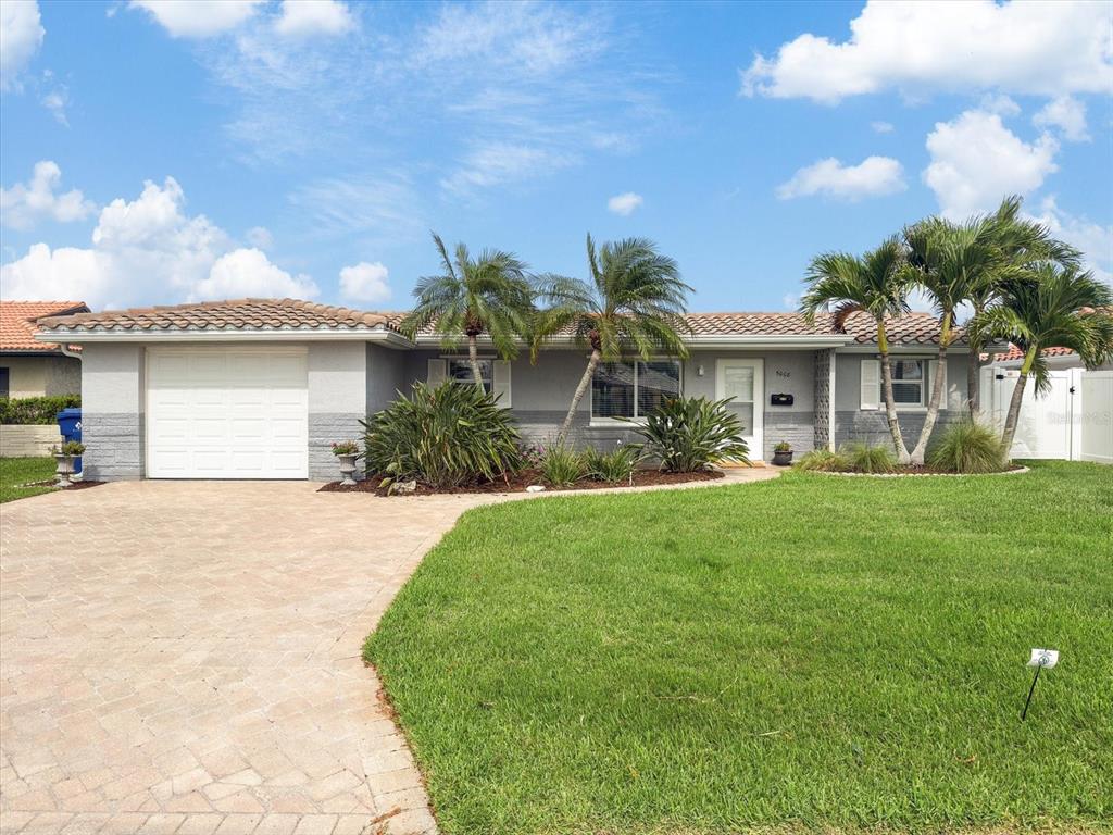 A single-story house with a paved driveway, palm trees, and a white garage door — 5008 DORY DRIVE, NEW PORT RICHEY, FL